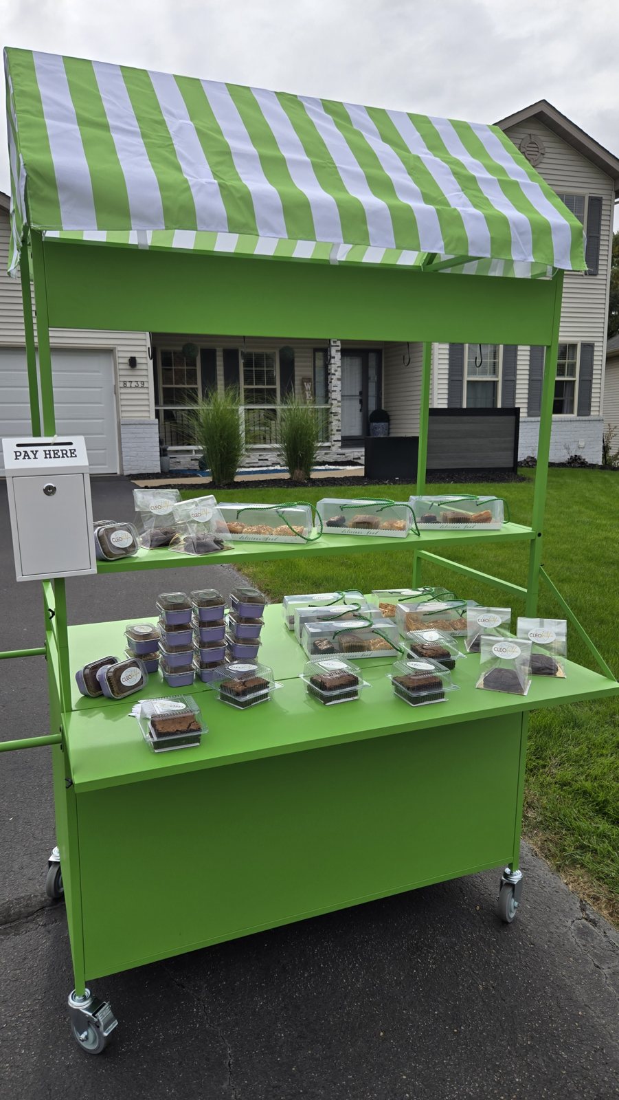 The CLEObetcha mobile cart with a green striped awning, stocked with treats